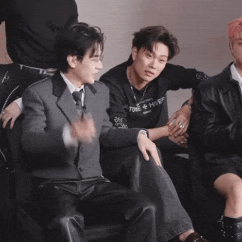 a man wearing a sweater that says hiver sits next to a man in a suit
