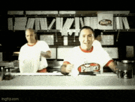 a man wearing a paulie 's shirt is standing in front of a counter