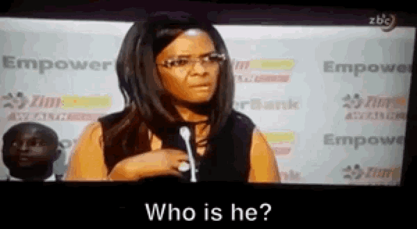 a woman with glasses is standing in front of a microphone and asking who is he