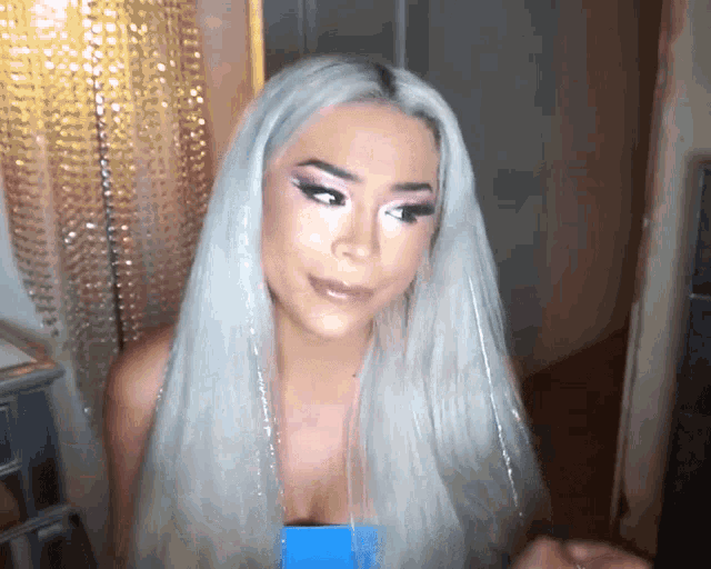 a woman with long white hair has a blue top on