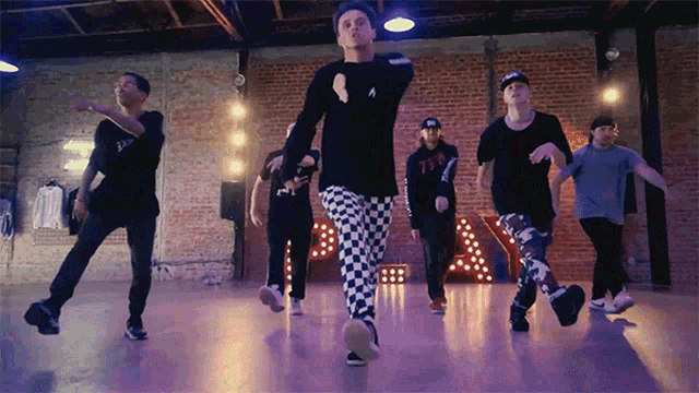 a group of men are dancing in front of a sign that says a on it
