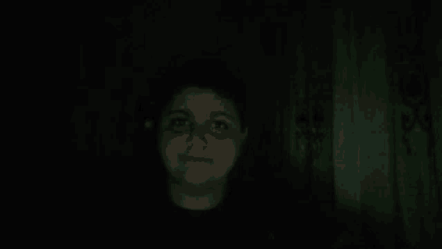 a girl with a black eye is standing in the dark .
