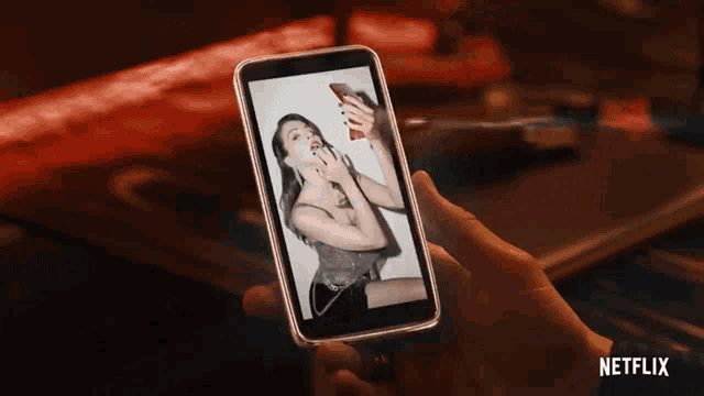 a person is holding a cell phone with a picture of a woman on it and a netflix logo behind them