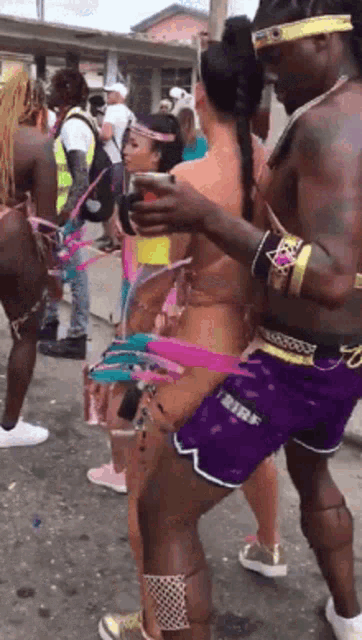 a man in purple shorts holds a cup over a woman 's waist