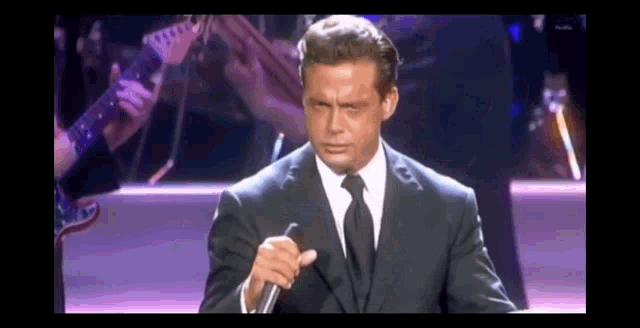 a man in a suit and tie is holding a microphone .