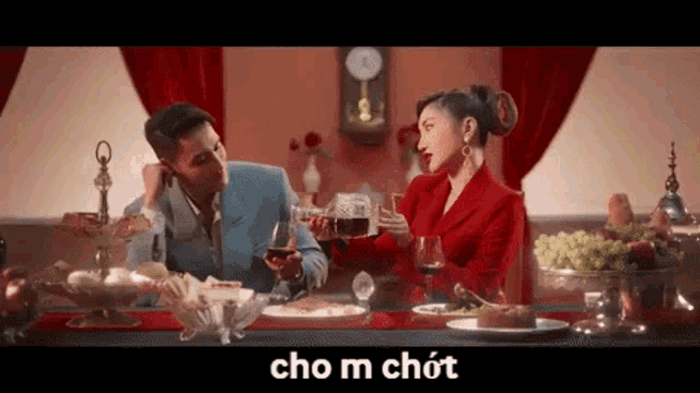 a man and a woman are sitting at a table with food and drinks .