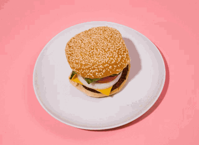 two hamburgers on a white plate on a pink surface