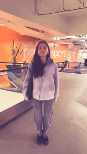 a woman stands in front of a sign that says macy 's
