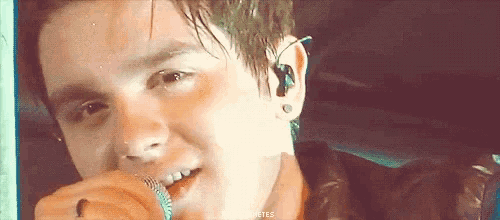 a close up of a young man singing into a microphone with the words " a few minutes " on the bottom right