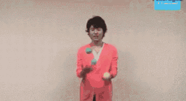 a man in a pink suit is holding a green ball in his hand .