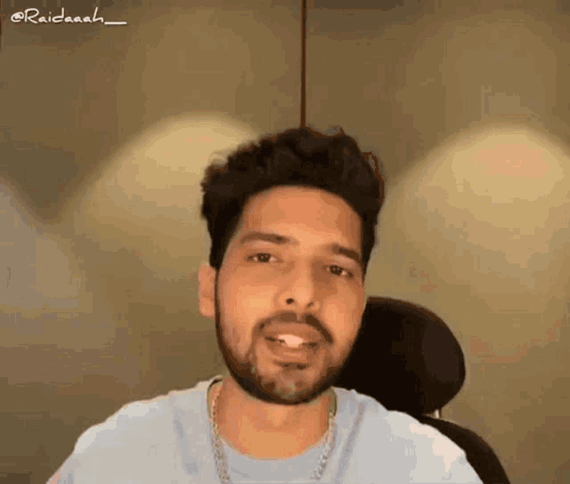 a man with a beard is wearing a blue shirt and a gold chain