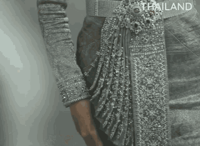 a close up of a woman wearing a gray dress with a belt and a belt around her waist .