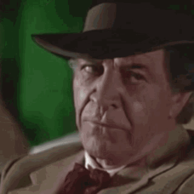 an older man wearing a hat and tie is smiling