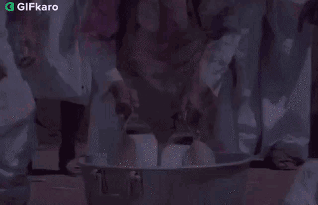 a group of people are pouring milk into a large bowl .