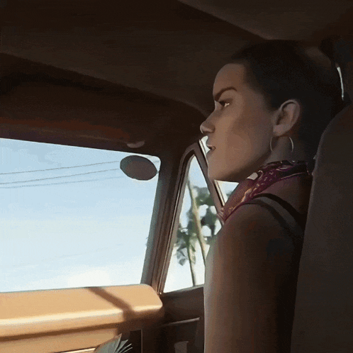 a woman in a car looking out the window with a palm tree in the background