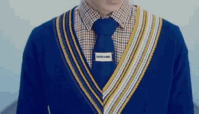 a man wearing a blue sweater and tie with a doyoung label on his neck