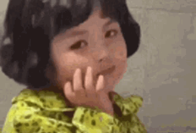 a little girl in a yellow shirt is making a funny face .