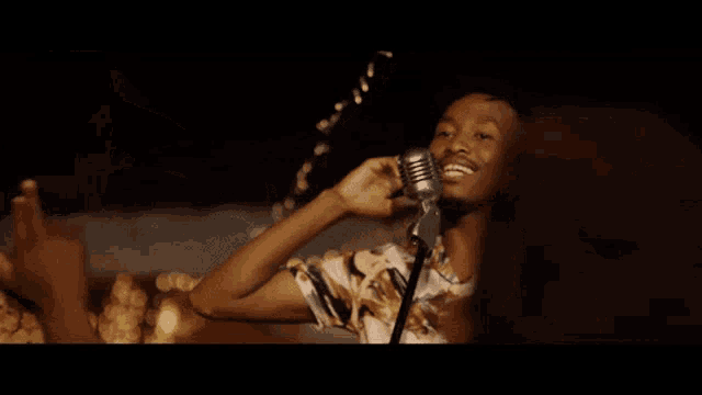 a man singing into a microphone with his arms outstretched