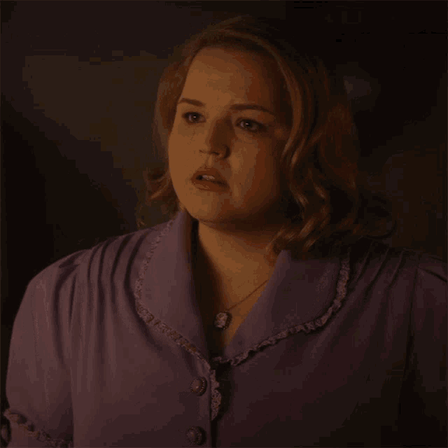 a woman in a purple dress with ruffles on the collar