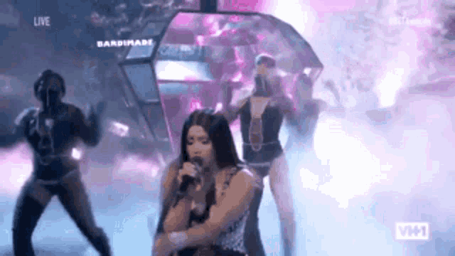 a woman is singing into a microphone while dancing on stage