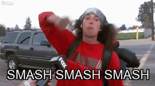 a man wearing a red shirt is holding a microphone and says smash smash smash .