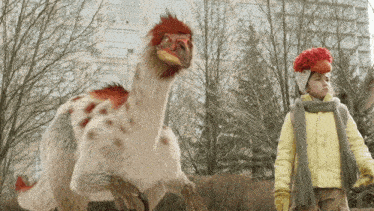 a girl in a yellow jacket stands next to a stuffed animal with a red head