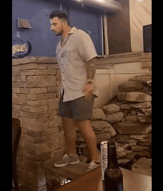 a man standing on a table with a bottle of beer
