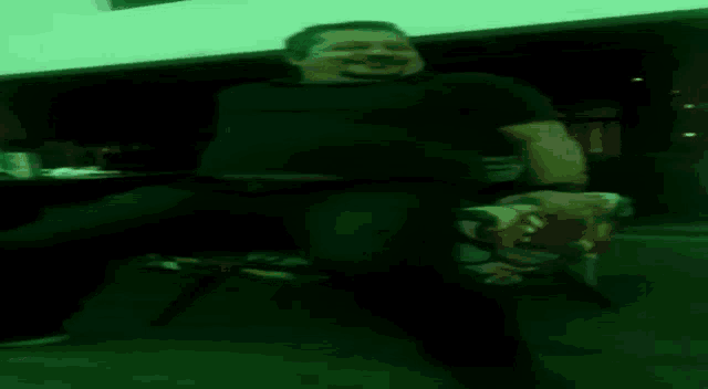 a man in a black shirt is sitting in a dark room
