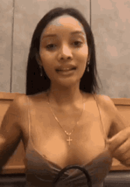 the woman is wearing a necklace with a cross on it and a bra .