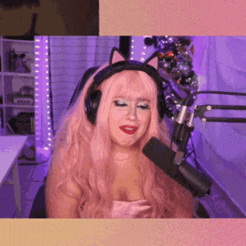 a woman with pink hair is sitting in front of a microphone wearing headphones and cat ears .