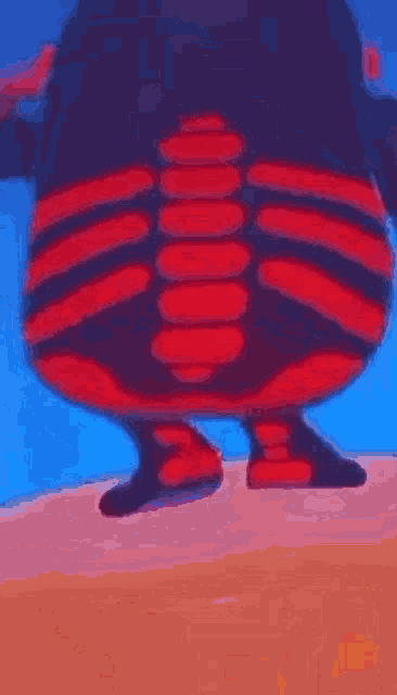 a cartoon character with a red and black striped shirt is standing on a sandy beach .