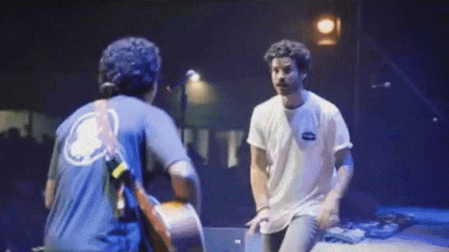 two men are playing guitars on a stage and one of them is wearing a shirt with a skull on it