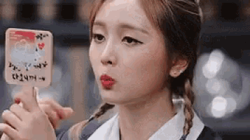 a woman is blowing a kiss while holding an ice cream cone in her hand .