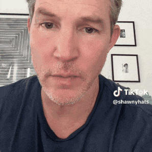 a man with a beard and a blue shirt has a tiktok sticker on his face