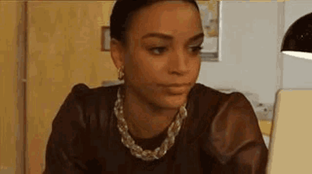 a woman is sitting at a table looking at a laptop .