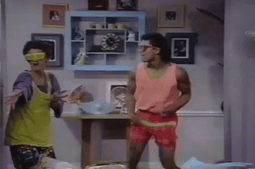 three men are dancing in a living room with a clock on the wall behind them
