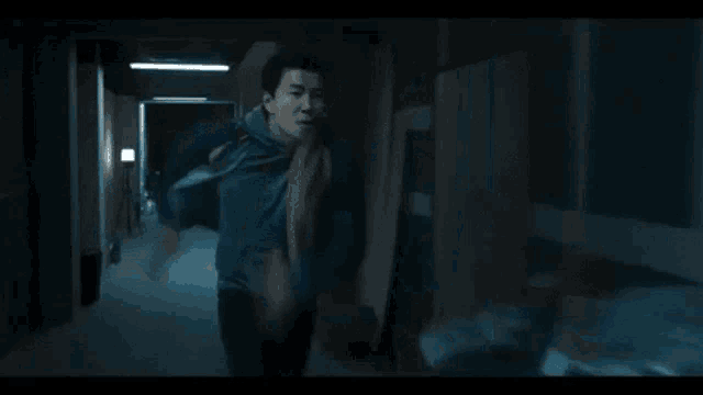 a man is running down a dark hallway .