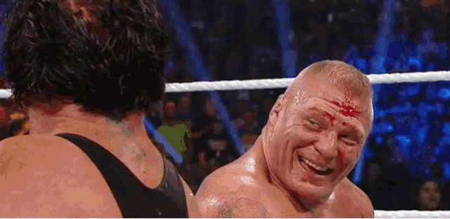 two men are wrestling in a ring and one of them is smiling .