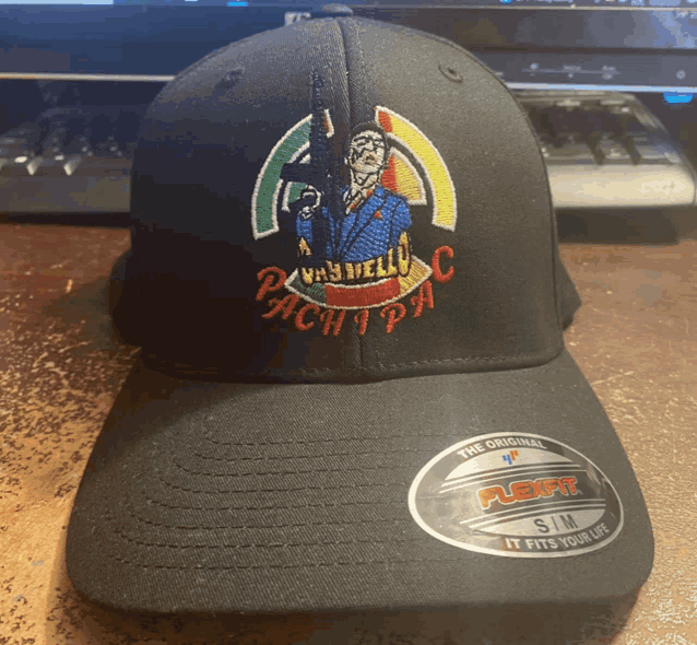 a black baseball cap with a man holding a gun and the word pachi pa on it