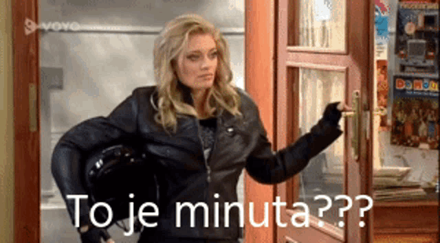 a woman in a leather jacket is standing in front of a door with the words to je minuta written on it