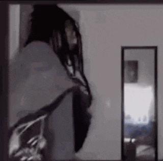 a man with dreadlocks is standing in front of a mirror .