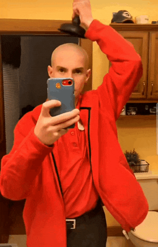 a man in a red jacket is taking a selfie with his cell phone