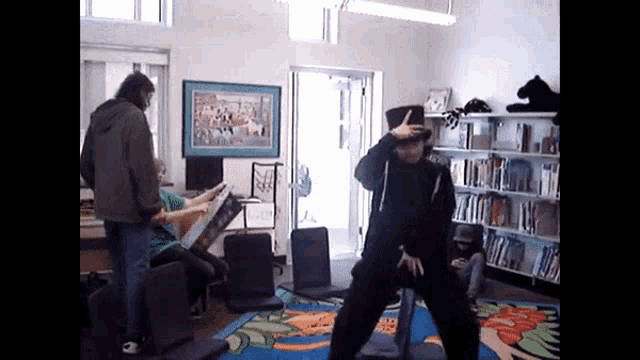 a man in a black hat is dancing in a room with a picture on the wall