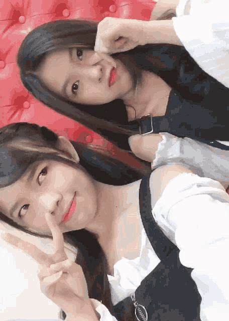 two girls are posing for a picture and one of them is giving the peace sign
