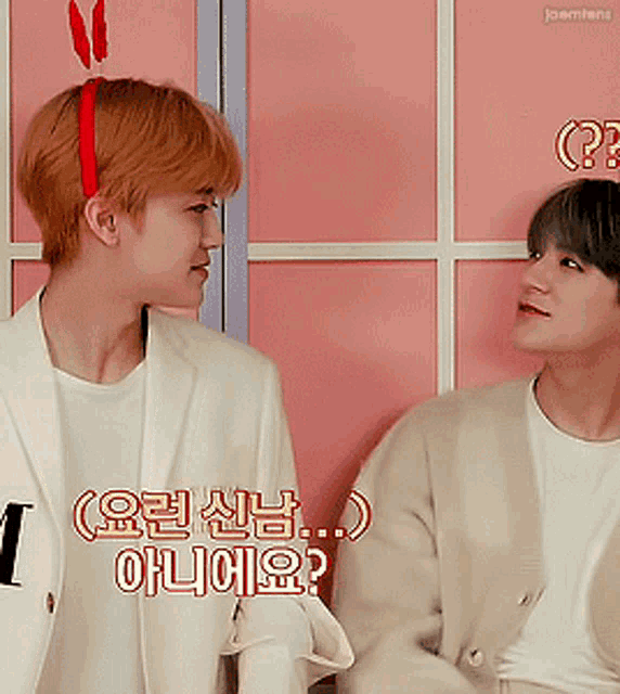 two men are sitting next to each other and one of them has a red headband on
