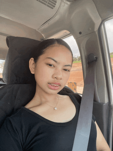 a young girl wearing a black shirt and a seat belt