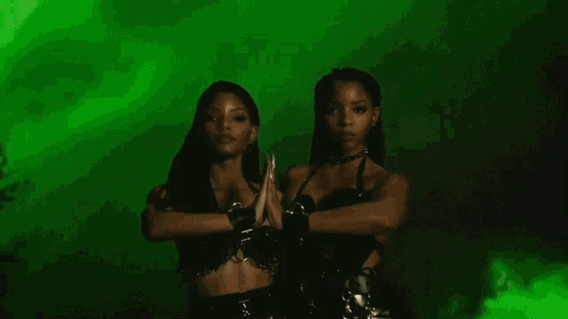 two women standing next to each other with their hands crossed