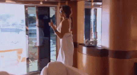 a woman in a white towel is holding a glass of wine .