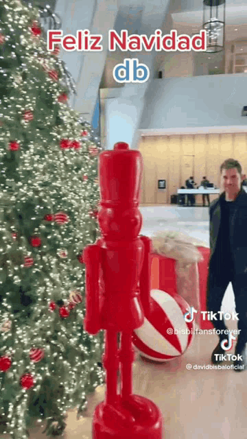 a man standing in front of a christmas tree with a nutcracker in front of it