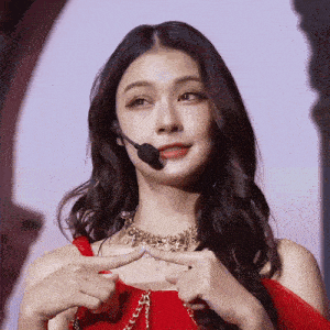 a woman wearing a red dress and a gold necklace has a microphone on her head